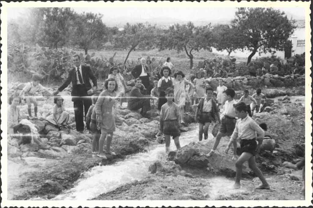 GRUPO DE PERSONAS OBSERVANDO EL DESAGÜE DEL CANAL PARA SU LIMPIEZA